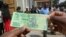 FILE: A man holds one of the new two-dollar banknotes issued by the Reserve Bank of Zimbabwe in Harare, Tuesday, Nov, 12, 2019.