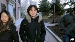 FILE - Xiaoning Sui, center, a Chinese national residing in British Columbia, Canada, leaves federal court in Boston, Feb. 21, 2020, after pleading guilty to paying to get her son into the University of California, Los Angeles, as a fake soccer recruit.