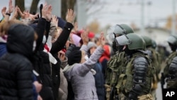 Demonstrators stand with their hands up in front of riot police line during an opposition rally to protest the official presidential election results in Minsk, Belarus, Nov. 1, 2020.