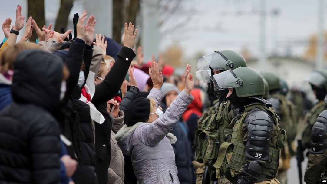 Demonstrators stand with their hands up in front of riot police line during an opposition rally to protest the official presidential election results in Minsk, Belarus, Nov. 1, 2020.
