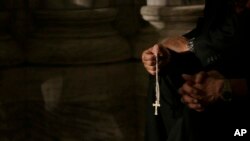 FILE - A member of the clergy prays the rosary at St. Patrick's Cathedral for evening prayer service in New York.