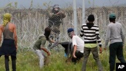 Migrant men trying to remove barbed wire along the fence clash with Macedonian police at the northern Greek border point of Idomeni, Greece, April 13, 2016. 