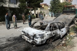 Security personnel inspect a damaged vehicle where rockets were fired from in Kabul, Afghanistan, July 20, 2021.