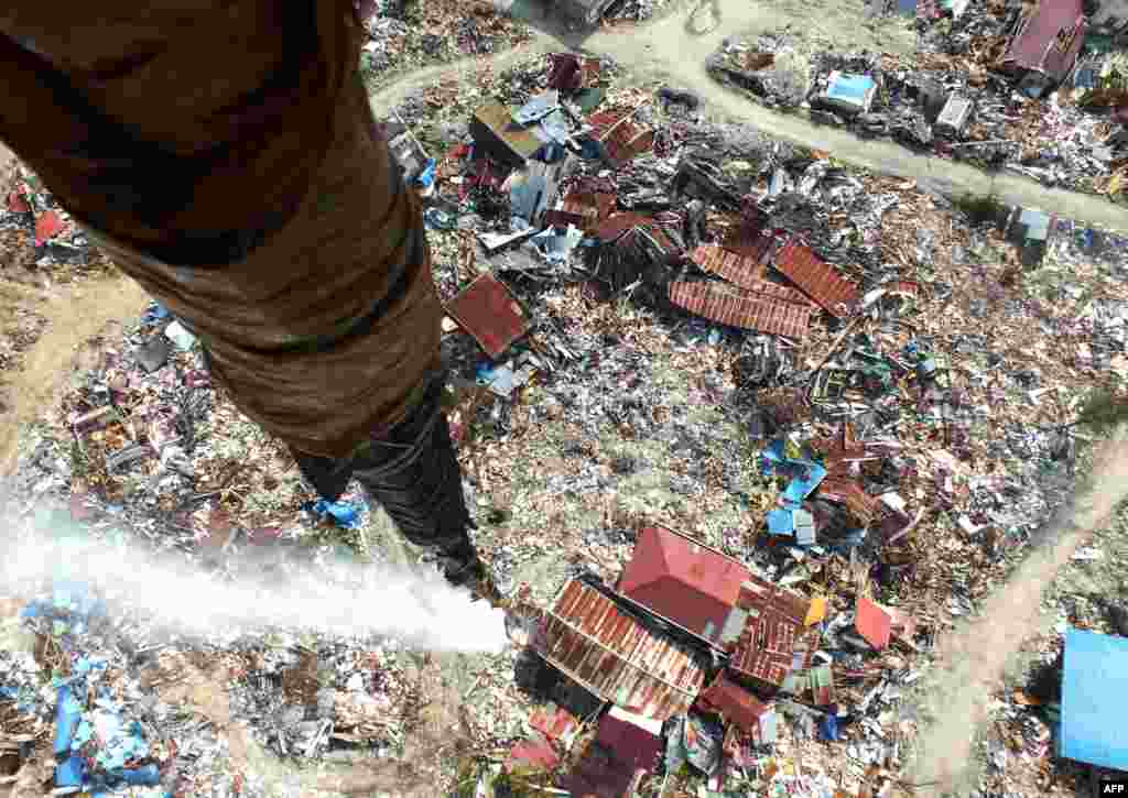 This picture taken from a helicopter shows disinfectant being released over an area affected by liquefaction due to the September 28 earthquake and where thousands are still feared buried, in an attempt to sterilize it, in Palu, Indonesia.