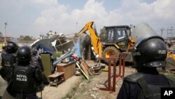 Nepalese policemen tear down temporary homes in a quake victims' shelter in downtown Kathmandu, Nepal, Tuesday, March 14, 2017.