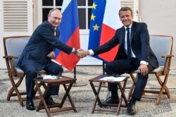 French President Emmanuel Macron, right, shakes hands with Russian President Vladimir Putin after their meeting at the fort of Bregancon in Bormes-les-Mimosas, southern France, Aug. 19, 2019.