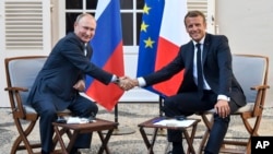 French President Emmanuel Macron, right, shakes hands with Russian President Vladimir Putin after their meeting at the fort of Bregancon in Bormes-les-Mimosas, southern France, Aug. 19, 2019. 