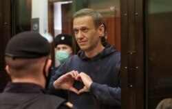 El líder opositor ruso Alexei Navalny hace un gesto de corazón a su esposa durante una audiencia en una corte de Moscú.