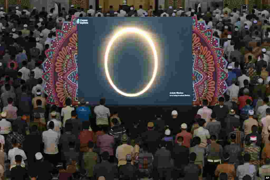 Muslim men perform a special &#39;kusoof&#39; prayer as a live report of the annular solar eclipse is broadcast on a large screen at a mosque in Surabaya, East Java, Indonesia.
