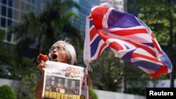 FILE - A supporter holds an apple and a copy of the Apple Daily newspaper outside the court to support media mogul Jimmy Lai, founder of Apple Daily, over charges related to an unauthorized assembly, Oct. 1, 2019, in Hong Kong, May 28, 2021. 