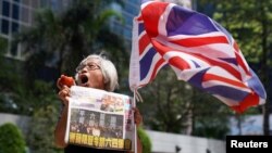 FILE - A supporter holds an apple and a copy of the Apple Daily newspaper outside the court to support media mogul Jimmy Lai, founder of Apple Daily, over charges related to an unauthorized assembly, Oct. 1, 2019, in Hong Kong, May 28, 2021. 