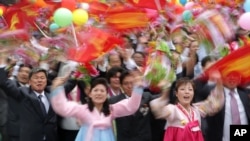 North Koreans wave flower bouquets and balloons as they march during a parade at the Kim Il Sung Square on Tuesday, May 10, 2016.