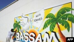 Un homme peint un mur dans le cadre du Festival international du dessin animé et de la bande dessinée d'Abidjan de Coco Bulles, en hommage aux victimes de l'attaque de Grand Bassam 2016 à Grand-Bassam, près d'Abidjan, le 18 mars 2017.