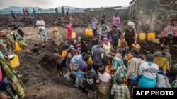 Des habitants de Goma autour d'un point d'eau couvert de lave après l'éruption du volcan Nyioragongo, dans l'est de la République Démocratique du Congo, 25 mai 2021. 