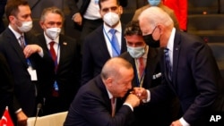 Turkey's President Recep Tayyip Erdogan, center, fist bumps with U.S. President Joe Biden, right, as he stands up to greet him during a plenary session at a NATO summit in Brussels, June 14, 2021. 