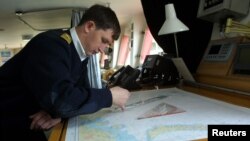FILE - A Russian seaman works on charts aboard the atomic icebreaker Yamal, docked in Murmansk.