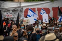 Protesters against Israel's Prime Minister Benjamin Netanyahu wave flags and banners outside his residence in Jerusalem, May 24, 2020.