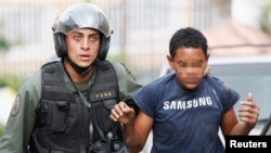 Un menor (al que le hemos tapado el rostro) es detenido por un guardia nacional, luego de las manifestaciones del sábado en Caracas.