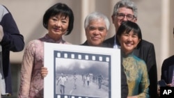 FILE - Pulitzer Prize-winning photographer Nick Ut, center, flanked by Kim Phuc, left, holds his Pulitzer Prize winning photo, as they wait to meet with Pope Francis during the weekly general audience in St. Peter's Square at The Vatican, May 11, 2022. 