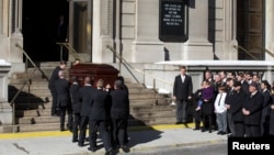 Mimi O'Donnell, former partner of actor Phillip Seymour Hoffman, holds their daughter Willa (in purple) next to their son Cooper as the casket arrives for Hoffman's funeral in the Manhattan borough of New York, Feb. 7, 2014. 