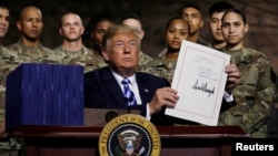 U.S. President Donald Trump holds up the National Defense Authorization Act after signing it in front of soldiers from the U.S. Army's 10th Mountain Division at Fort Drum, New York, Aug. 13, 2018. 