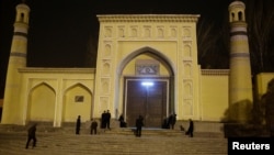 FILE - Men stand outside the Id Kah Mosque before morning prayers in Kashgar, Xinjiang Uighur Autonomous Region, China, March 23, 2017. 