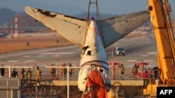 Sebuah derek mengangkat bagian ekor pesawat selama operasi penyelamatan pesawat Boeing 737-800 Jeju Air yang jatuh dan terbakar pada 29 Desember 2024 di Bandara Internasional Muan, Muan pada 3 Januari 2025. (Foto: AFP)