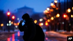 FILE - A person wearing a face mask as a precaution against the coronavirus walks during a winter storm in Philadelphia, Feb. 1, 2021. 