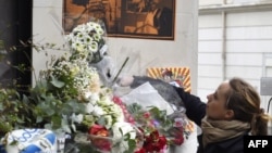 A woman places flowers near the offices of French satirical newspaper Charlie Hebdo, following an attack on the offices Wednesday by armed gunmen that left 12 dead, in Paris, Jan. 8, 2015.