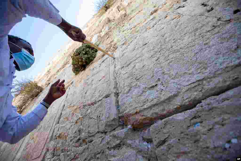 A worker removes prayer notes left by visitors in gaps between stones at the Western Wall, the holiest site where Jews can pray in Jerusalem's old city, ahead of Rosh Hashana, the Jewish new year. The notes are buried in a nearby cemetery.