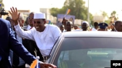 Le président tchadien Idriss Deby se penche de sa voiture pour saluer la foule après son arrivée à Khartoum, Soudan, 08 mars 2016. Deby a été proclamé vainqueur au premier tour de l’élection présidentielle du 10 mars 2016 au Tchad avec plus de 69%. epa/MORWAN ALI