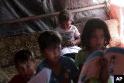 FILE - Syrian children study at a refugee camp near Amman, Jordan, on June 5, 2023.