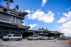 FILE - Seabees coordinate transportation of U.S. Navy sailors assigned to the aircraft carrier USS Theodore Roosevelt who have tested negative for coronavirus disease (COVID-19) to locations off base at Naval Base Guam, April 10, 2020.