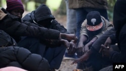 Des migrants soudanais attendent près d'un feu dans la forêt à Ouistreham, France, le 5 octobre 2017.