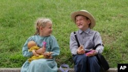 FILE - Nine-year-old Myron King and his six-year-old sister Lucy Anne enjoy a laugh while eating lunch and caring for their pretend baby in Louisville, Ky., June 24, 2010.