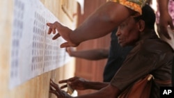 People look for their names on the electoral roll before casting their ballot at a polling station in Lome, Togo, April 25, 2015. 