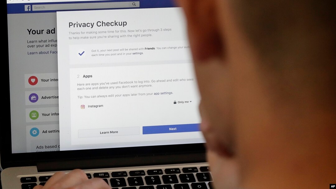 FILE - A man poses a photo in front of a computer showing Facebook ad preference pages, in San Francisco, California, March 26, 2018.