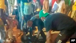 Watu wakiwasaidia waathiriwa wa mkanyagano nje ya uwanja wa ulikofanyika mchezo wa soka wa Kombe la Mataifa ya Afrika mjini Yaounde kati ya Cameroon na Comoro Jan. 24, 2022. 