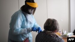 Seorang petugas medis memberikan suntikan vaksin COVID-19 produksi Pfizer-BioNTech kepada seorang lansia di Froendenberg, Jerman (foto: ilustrasi). 