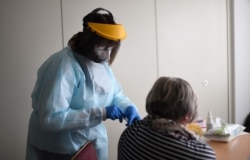 A medical assistant vaccinates a resident of a nursing home with an injection of the Pfizer-BioNTech COVID-19 vaccine at the nursing home for seniors, in Froendenberg, western Germany, Jan. 22, 2021.
