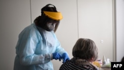 A medical assistant vaccinates a resident of a nursing home with an injection of the Pfizer-BioNTech COVID-19 vaccine at the nursing home for seniors, in Froendenberg, western Germany, Jan. 22, 2021. 