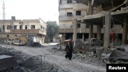 A man walks on rubble at a damaged site in the rebel held besieged town of Hamouriyeh, eastern Ghouta, near Damascus, Syria, Feb. 21, 2018.