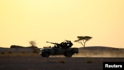 FILE - The Polisario Front soldiers drive a pick-up truck mounted with an anti-aircraft weapon during sunset in Bir Lahlou, Western Sahara, Sept. 9, 2016. 