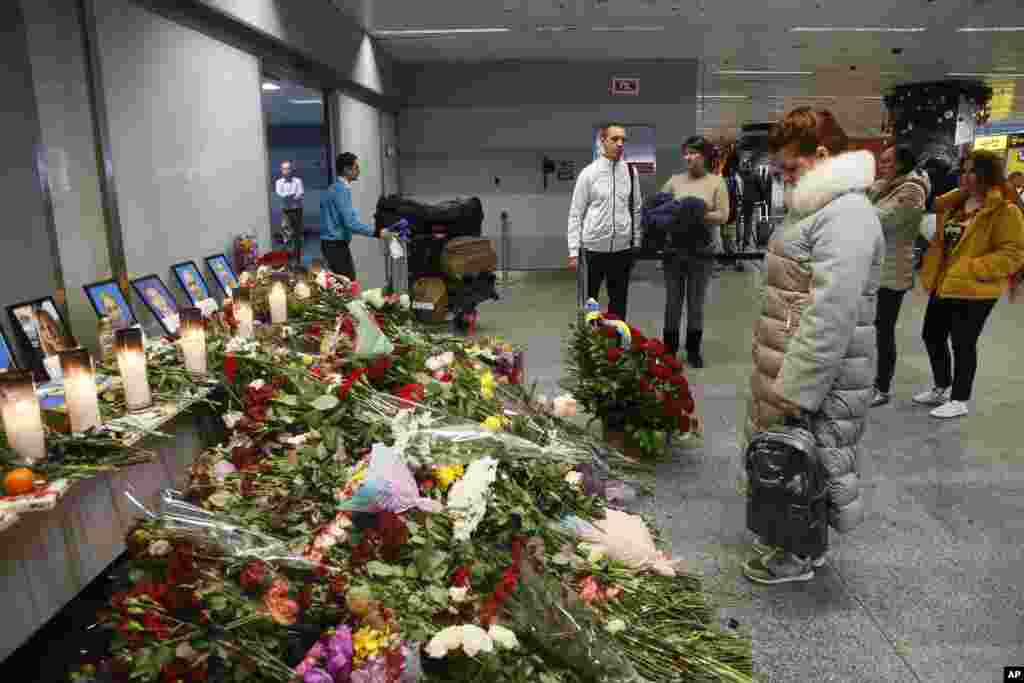 حاضران در فرودگاه بین المللی کی&zwnj;یف به یادبود خلبانان و پرسنل هواپیمای اوکراینی سقوط کرده در ایران می&zwnj;نگرند.