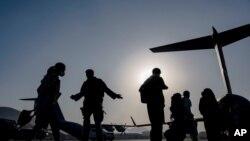 FILE - U.S. Air Force airmen guide evacuees aboard a U.S. Air Force C-17 at Hamid Karzai International Airport in Kabul, Afghanistan, Aug. 24, 2021, in this image provided by the U.S. Air Force. (Senior Airman Taylor Crul/U.S. Air Force via AP)