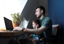 Economist and leader of a protest Shota Dighmelashvili and his son Neo sit in front of a computer at home in Tbilisi, Georgia, July 18, 2019.