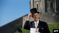 FILE - British radio and television presenter Nicholas Parsons poses with his Commander of the Order of the British Empire (CBE) medal given to him by Queen Elizabeth II at an Investiture ceremony at Windsor Castle, Berkshire, April 15, 2014. 