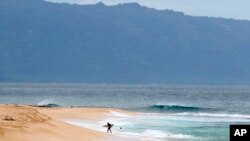 ARCHIVO - Un surfista sale del agua en la costa norte de Oahu cerca de Haleiwa, Hawái, el 31 de marzo de 2020. 