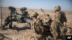FILE - In this June 10, 2017 photo provided by Operation Resolute Support, U.S. doldiers with Task Force Iron maneuver an M-777 howitzer, so it can be towed into position at Bost Airfield, Afghanistan. 