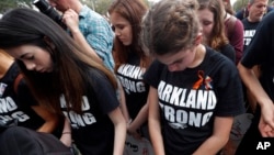 Student survivors from Marjory Stoneman Douglas High School bow their heads as the names of shooting victims are read, at a rally for gun-control reform on the steps of the state Capitol in Tallahassee, Fla., Feb. 21, 2018.